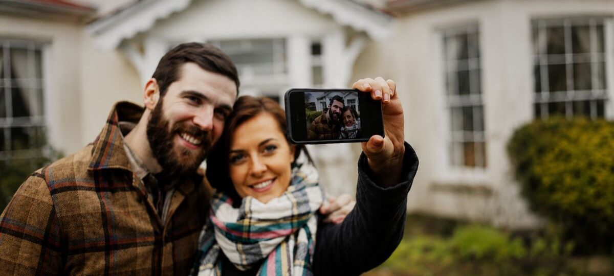 Casal tirando foto pelo celular em frente a uma casa de campo ampla para alugar no Vale do Café.