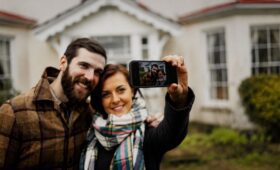 Casal tirando foto pelo celular em frente a uma casa de campo ampla para alugar no Vale do Café.