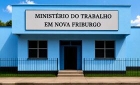 Fachada do edifício do Ministério do Trabalho em Nova Friburgo com paredes azuis, placa de identificação na entrada, janelas de vidro e portão de ferro preto.
