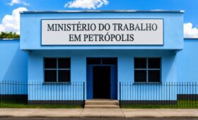 Fachada de prédio público na cor azul com uma placa branca contendo a escrita Ministério do Trabalho em Petrópolis em letras pretas.