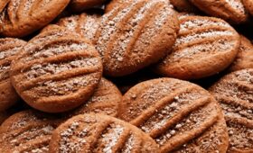 Vista aproximada de biscoitos de canela artesanais dourados com marcas de garfo e polvilhados com açúcar e canela.