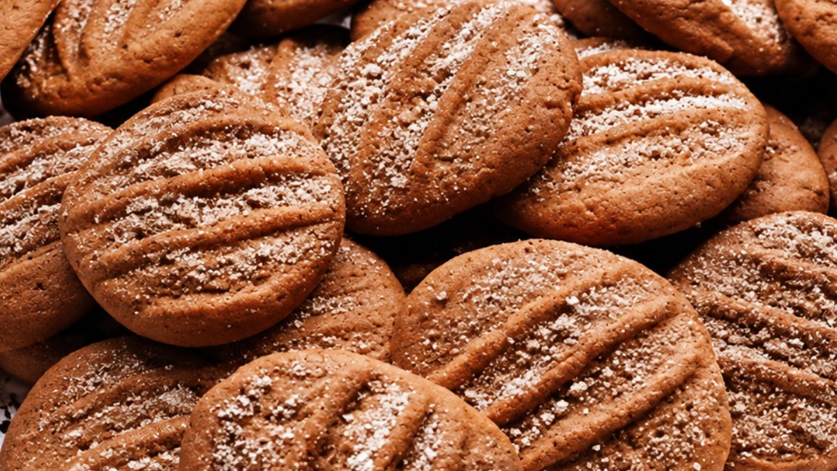 Vista aproximada de biscoitos de canela artesanais dourados com marcas de garfo e polvilhados com açúcar e canela.