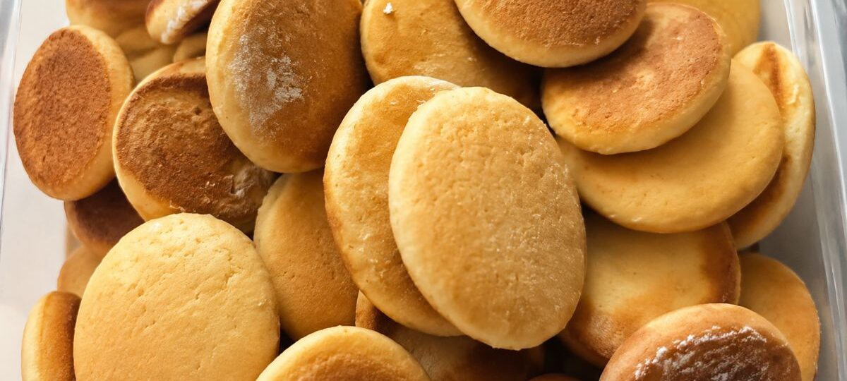 Close em close em uma pilha de biscoitos de mel caseiros redondos assados até dourarem perfeitamente em um recipiente.