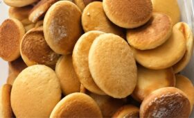Close em close em uma pilha de biscoitos de mel caseiros redondos assados até dourarem perfeitamente em um recipiente.