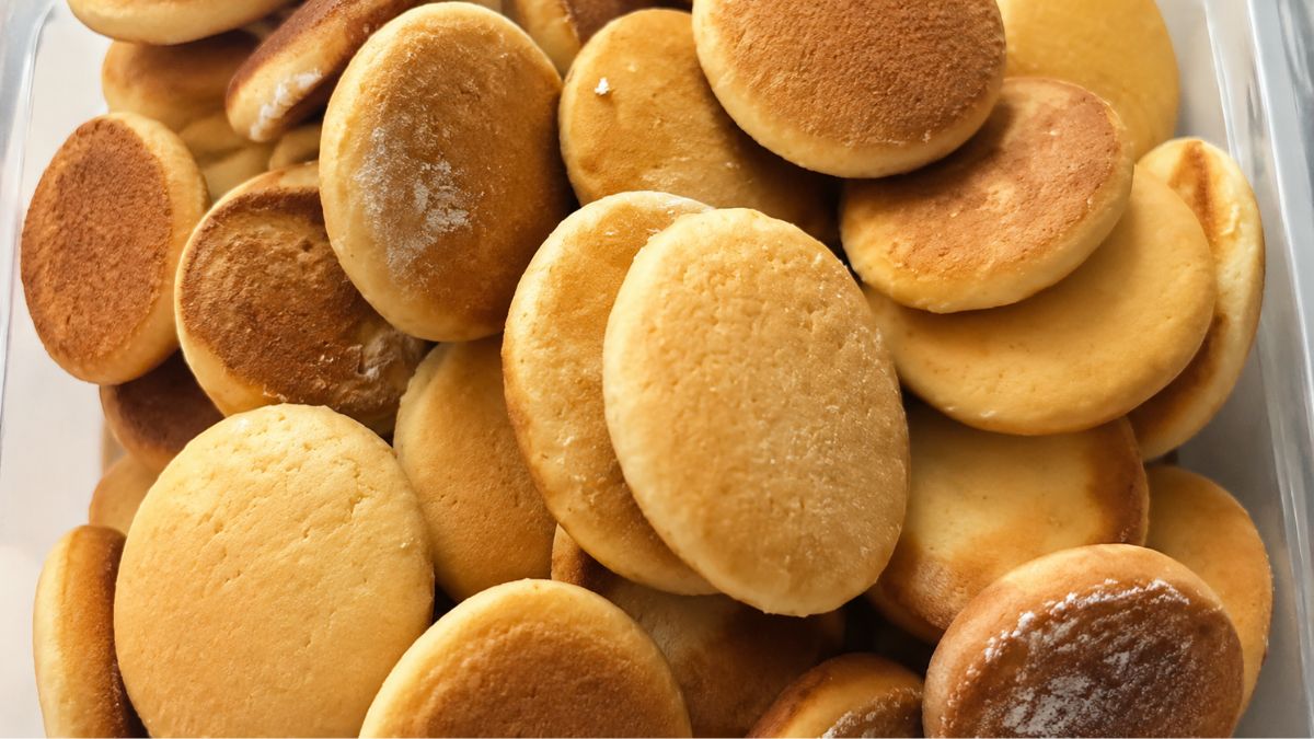 Close em close em uma pilha de biscoitos de mel caseiros redondos assados até dourarem perfeitamente em um recipiente.