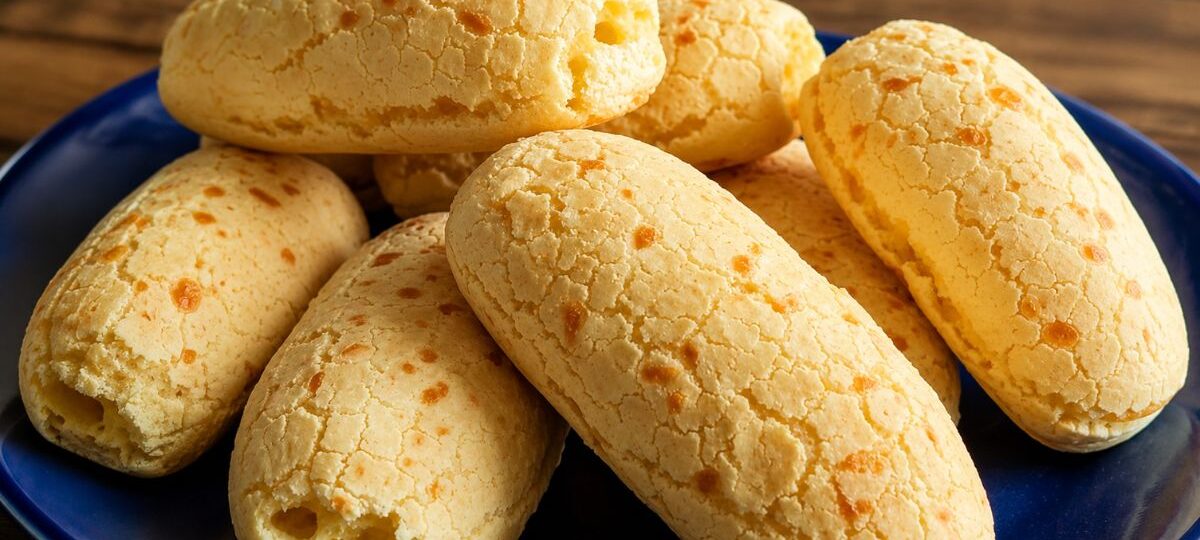 Biscoitos de tapioca assados e crocantes servidos em um prato azul sobre mesa de madeira rústica.