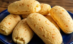 Biscoitos de tapioca assados e crocantes servidos em um prato azul sobre mesa de madeira rústica.