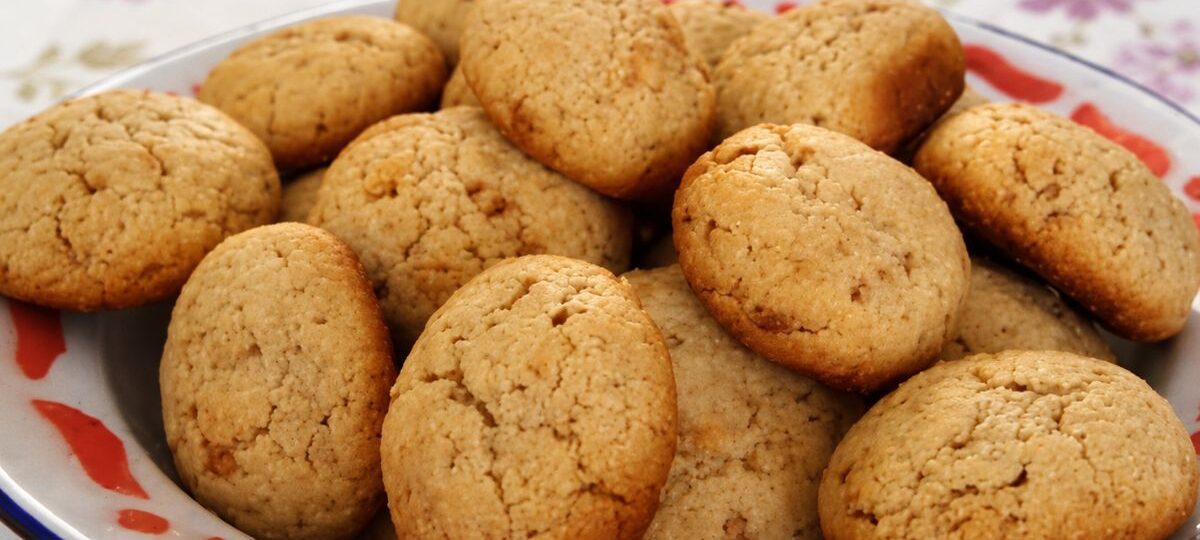 close-up de biscoitos caseiros dourados com aveia e mel empilhados em uma tigela rústica sobre toalha de mesa