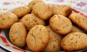 close-up de biscoitos caseiros dourados com aveia e mel empilhados em uma tigela rústica sobre toalha de mesa