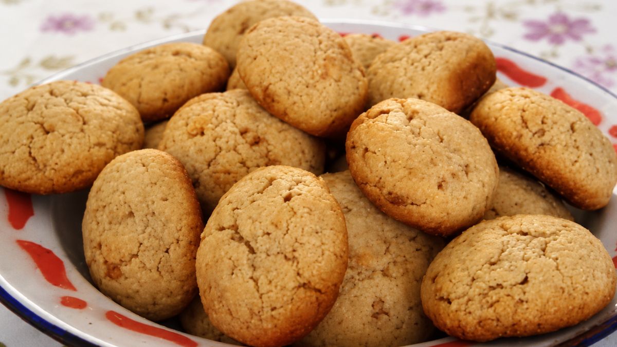 close-up de biscoitos caseiros dourados com aveia e mel empilhados em uma tigela rústica sobre toalha de mesa