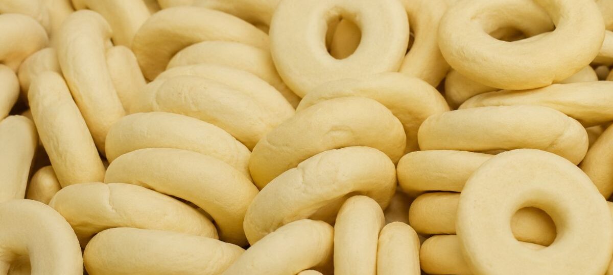 Vários biscoitos de araruta caseiros em formato de rosquinha com superfície clara e lisa empilhados.