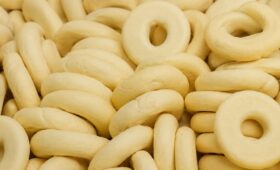Vários biscoitos de araruta caseiros em formato de rosquinha com superfície clara e lisa empilhados.