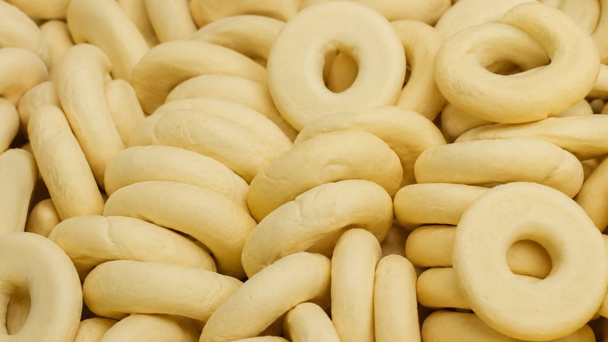 Vários biscoitos de araruta caseiros em formato de rosquinha com superfície clara e lisa empilhados.
