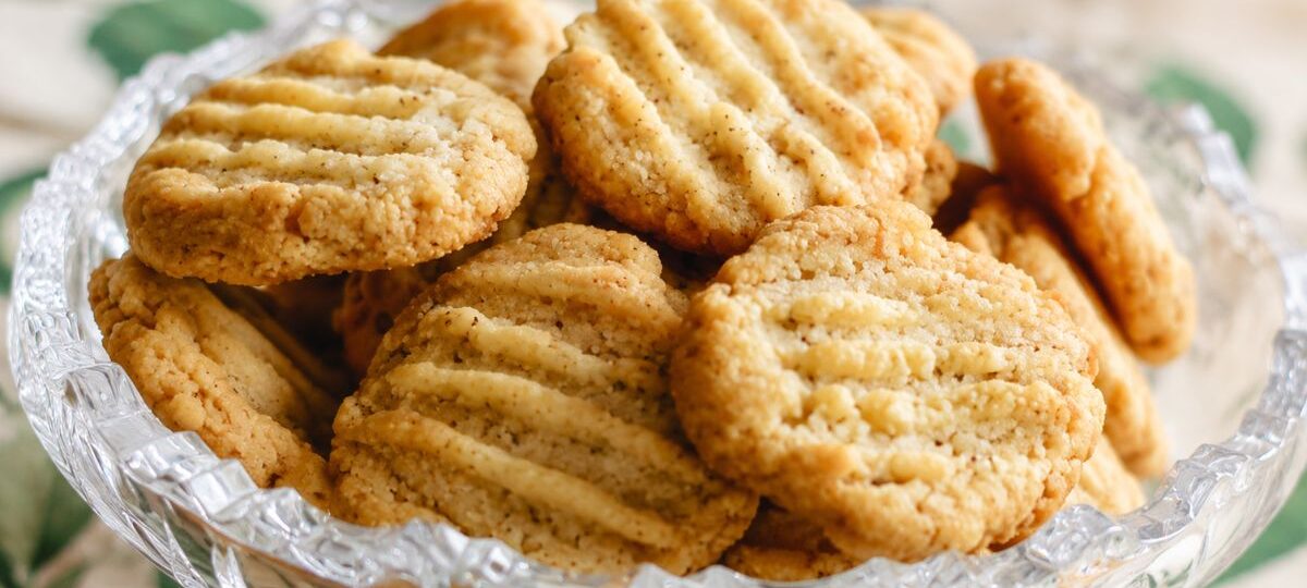 Um close em uma taça de cristal lapidado recheada com biscoitos de erva-doce caseiros dourados com marcas de garfo.
