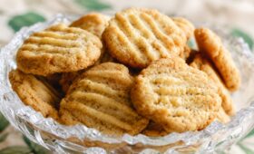 Um close em uma taça de cristal lapidado recheada com biscoitos de erva-doce caseiros dourados com marcas de garfo.
