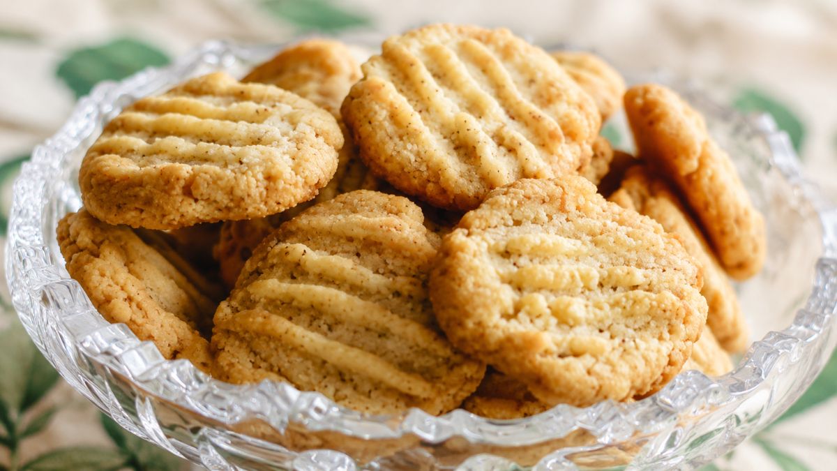 Um close em uma taça de cristal lapidado recheada com biscoitos de erva-doce caseiros dourados com marcas de garfo.