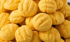 Close em uma pilha de biscoitos de maracujá caseiros amarelos redondos com marcas de garfo na parte superior.