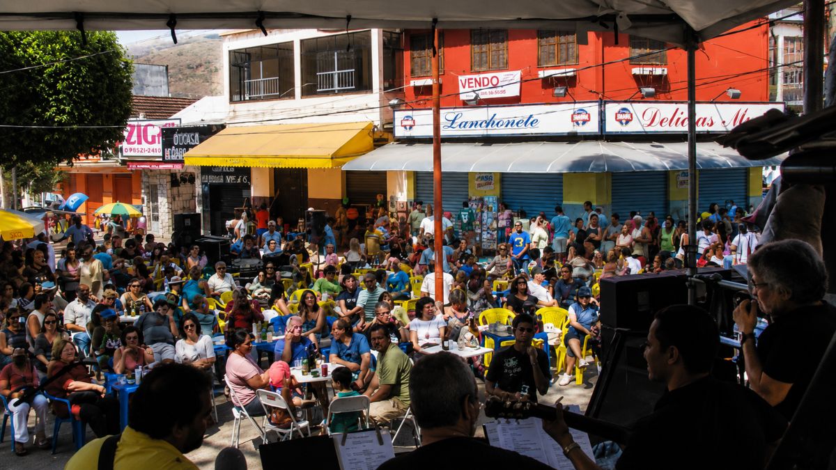 Grande publico sentado em cadeiras de praia ao ar livre na Praca Doutor Joao Neri durante evento de musica em Mendes.