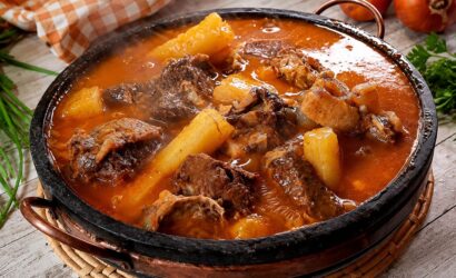 Panela de pedra rústica servindo vaca atolada da roça quente com pedaços suculentos de costela bovina e mandioca cozida em caldo cremoso.
