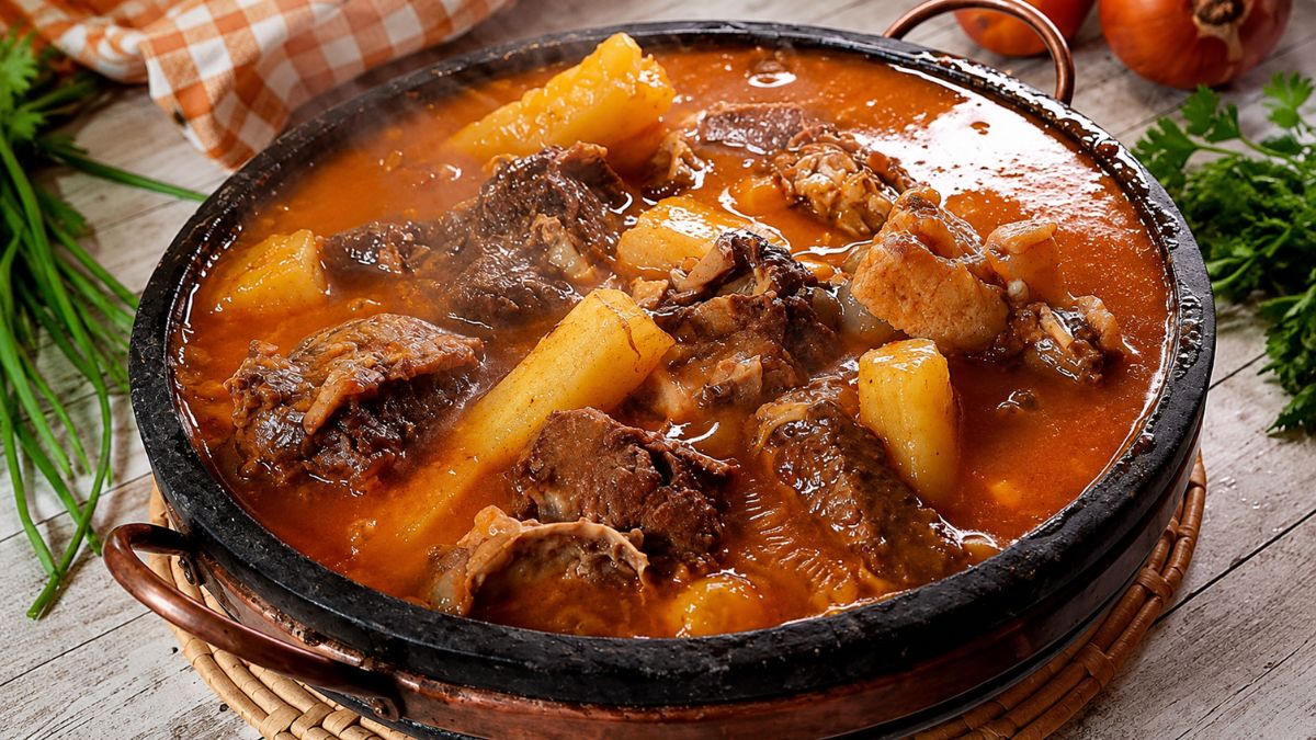 Panela de pedra rústica servindo vaca atolada da roça quente com pedaços suculentos de costela bovina e mandioca cozida em caldo cremoso.